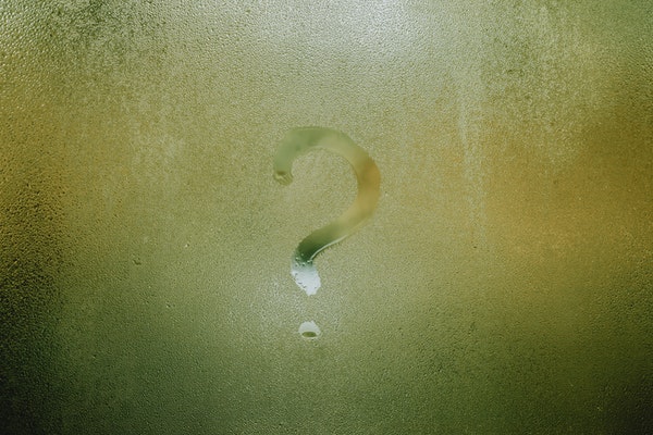 A question mark drawn on a window pane with condensation.