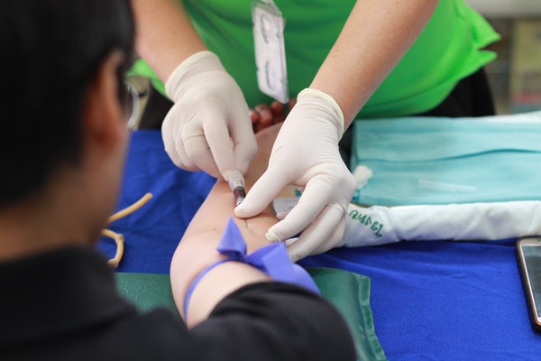 A medical professional drawing blood from the arm of a patient.