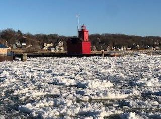 A red lighthouse on a sunny winter day with snow in the foreground in Holland, Michigan.