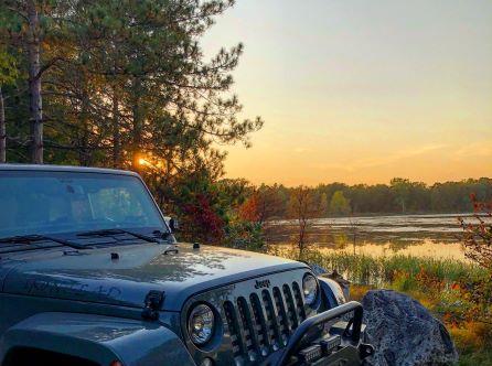 A Jeep Wrangler parked near a lake at sunset in Kalamazoo, Michigan.