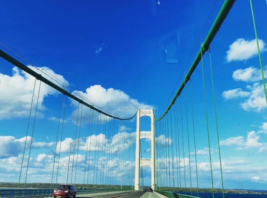 The Mackinac Bridge on a sunny day with large white clouds.