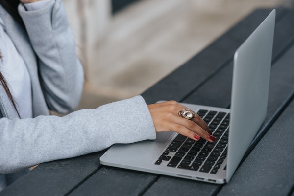 Woman wearing gray sweater typing on a laptop