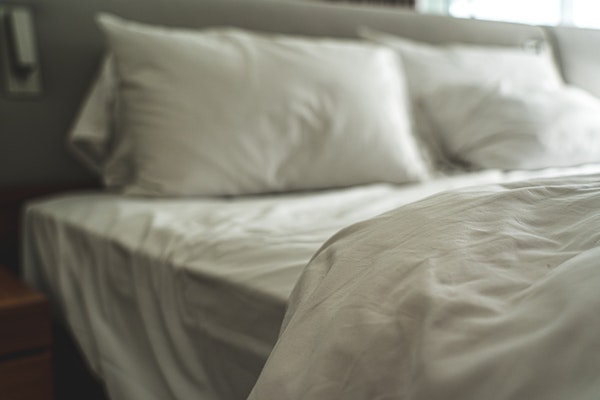 Up close of bed with white covers pulled back from pillows