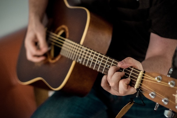 Up close shot of man playing brown guitar