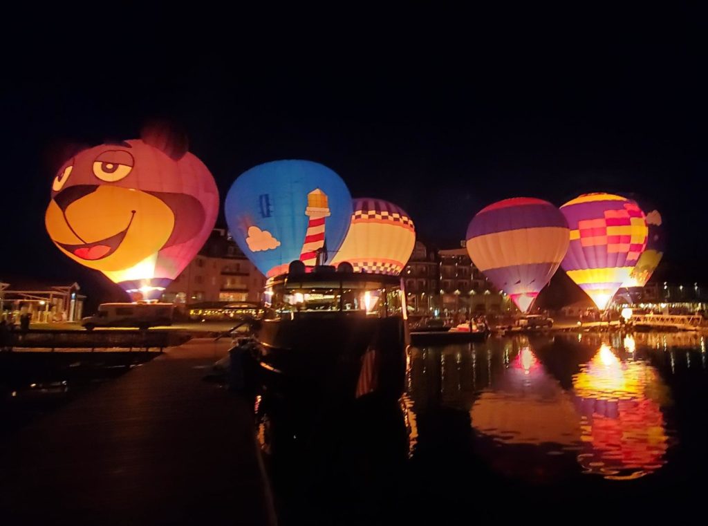 Hot air balloons lit up at night on the shore of the bay in Bay Harbor, Michigan.