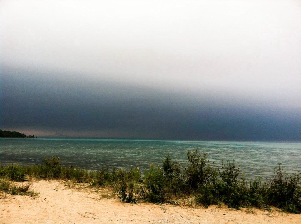 A beach at the Emmet County Wilderness State Park under dark skies.