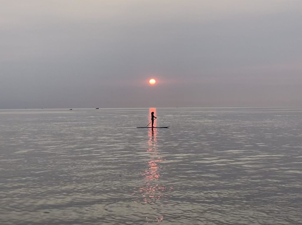 The silhouette of a paddleboarder on a lake in Grand Haven, Michigan at sunset.