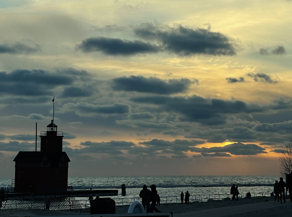 A lighthouse at sunset in Holland, Michigan on a partly cloudy evening.