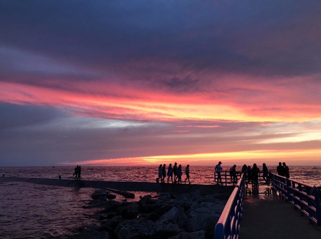 People on a pier at sunset congregating overlooking the lake in Holland State Park in Michigan.