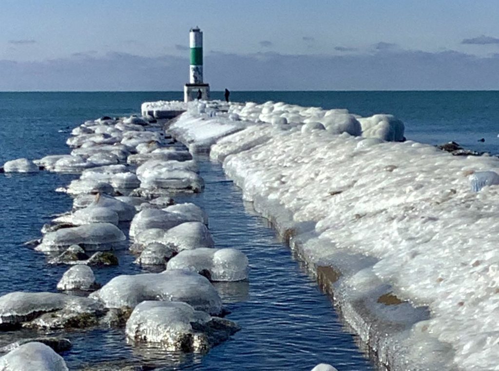 An icy pier and lighthouse in Holland State Park, Michigan.