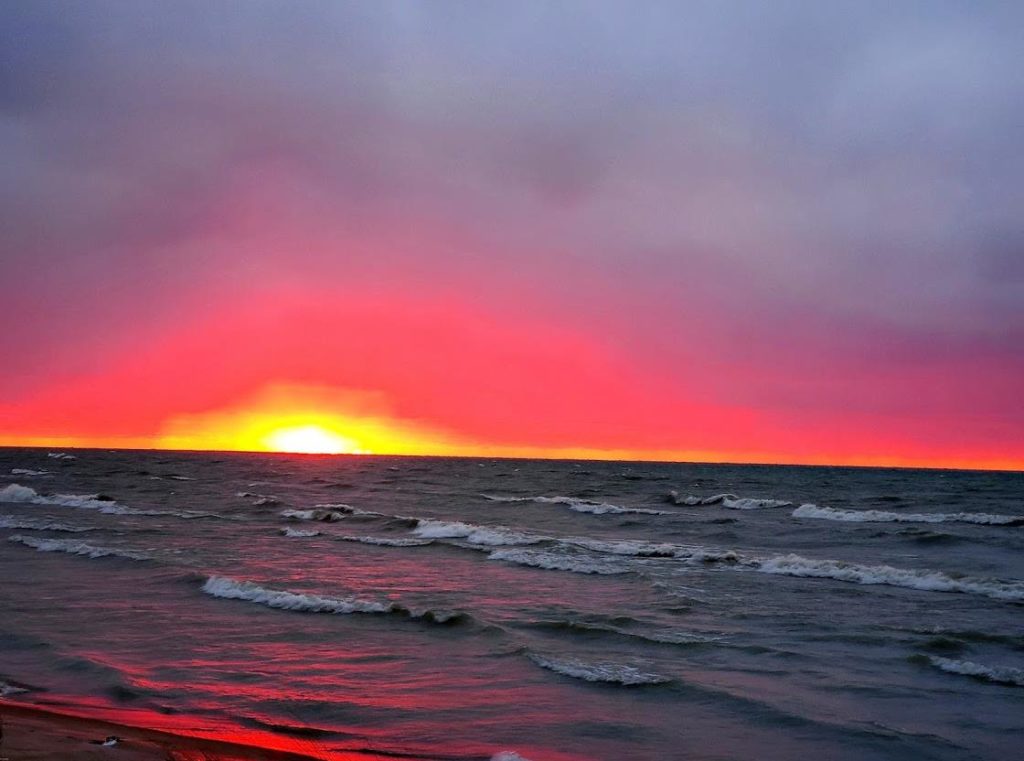 Waves lapping on a shore at sunset in Michigan.