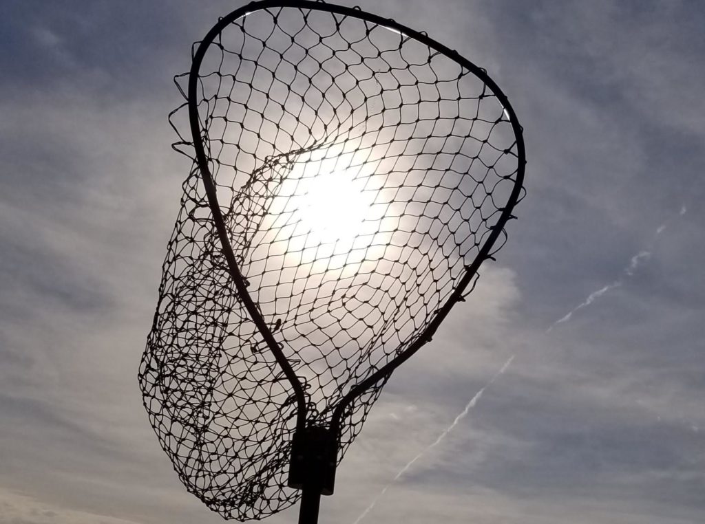 A fishing net with the sun shining through it on a cloudy day.