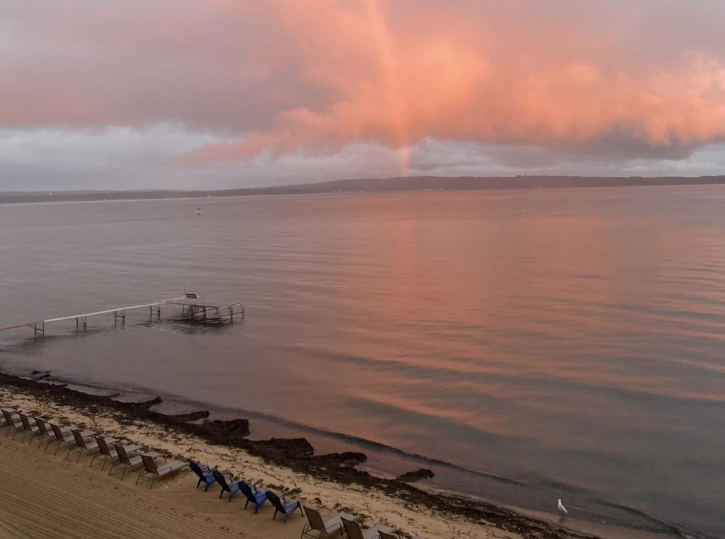 A faint rainbow extending from the opposite shore on a cloudy evening in Traverse City, MI.