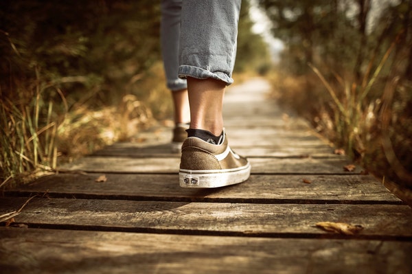 Up close of person's shoes walking over wooden bridge in woods