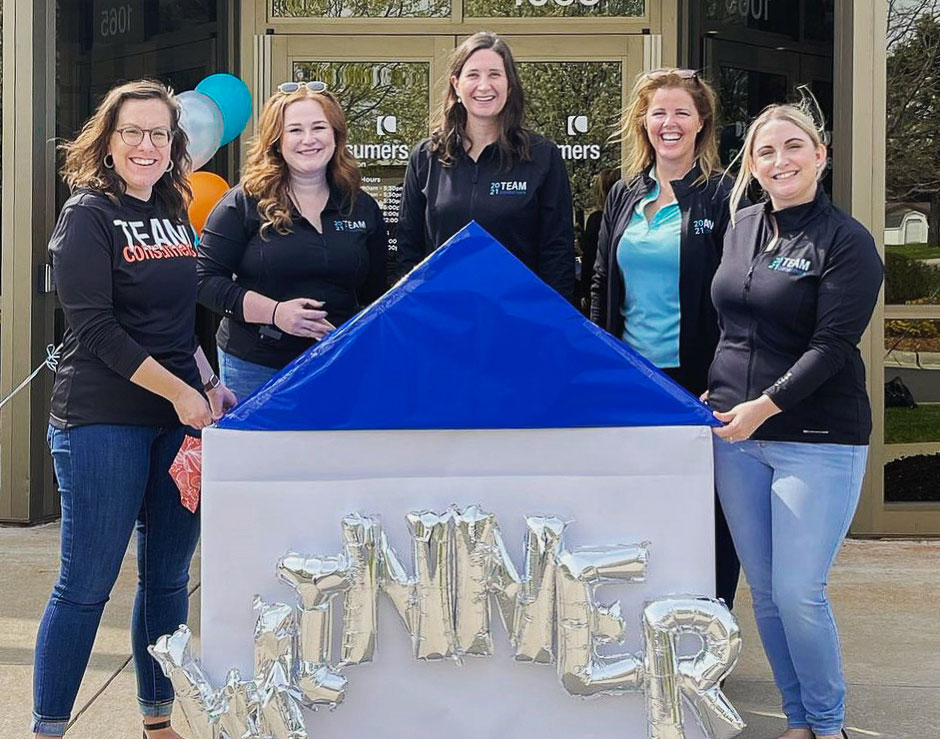 Consumers Marketing team smiling in the front of a "winner" sign