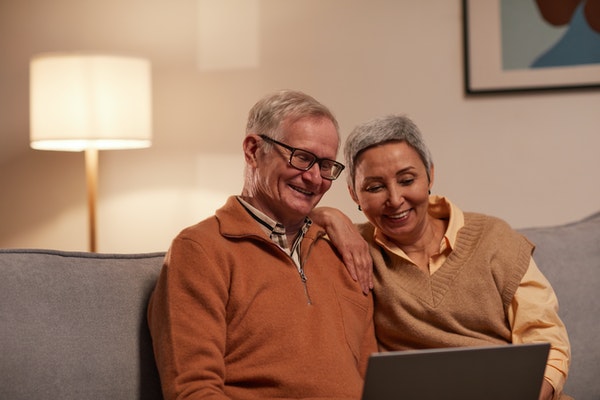 Mature husband and wife looking at computer on sofa