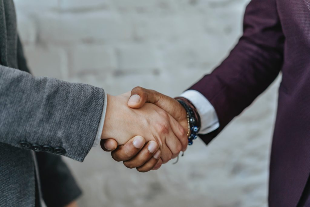 Two people is business suits shake hands.