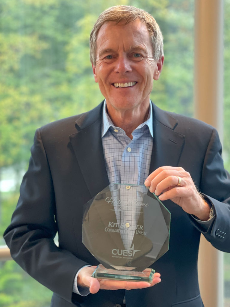 Consumers President & CEO Kit Snyder smiling as he holds his CUES Hall of Fame award.