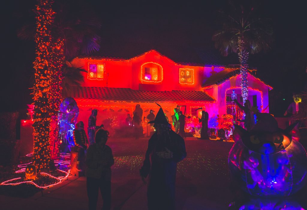 A house lit up with red lights as people gather in the front yard on Halloween