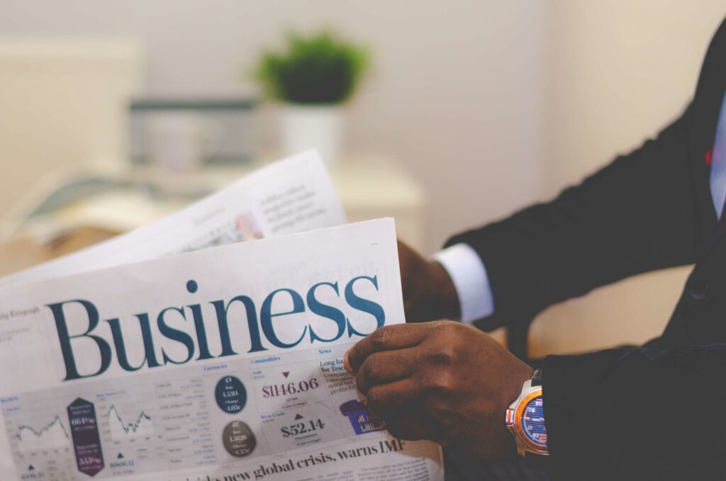 A man in a suit reading the business section of a newspaper.