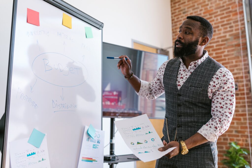 A business professional standing at a whiteboard as he brainstorms goals for the next year.