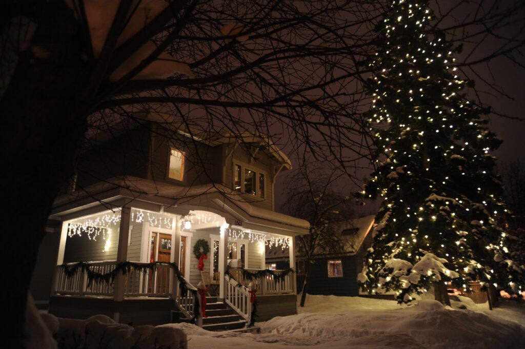 A house lit up with holiday lights on a dark, snowy night.