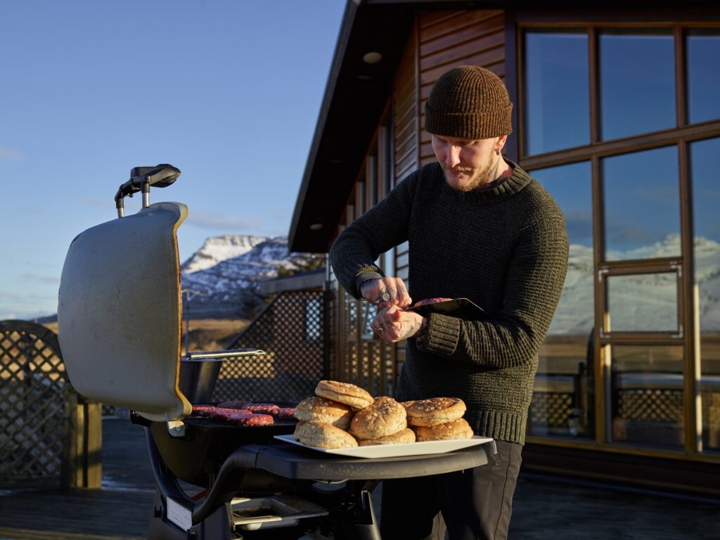 A man grilling hamburgers outside in cold weather.
