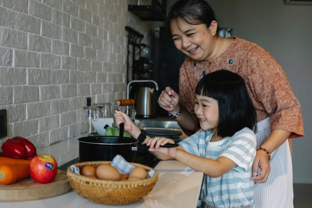 A woman and her granddaughter cooking together in a kitchen.