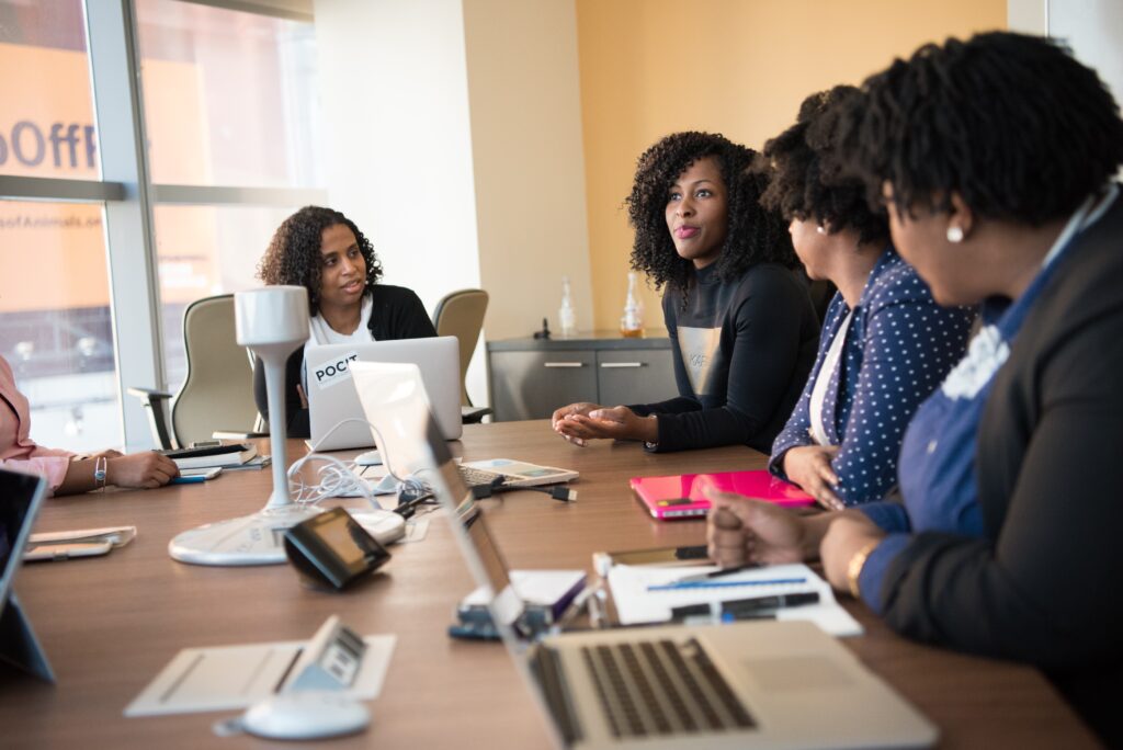 Young, female Black business professionals sit around a conference table as they collaborate.