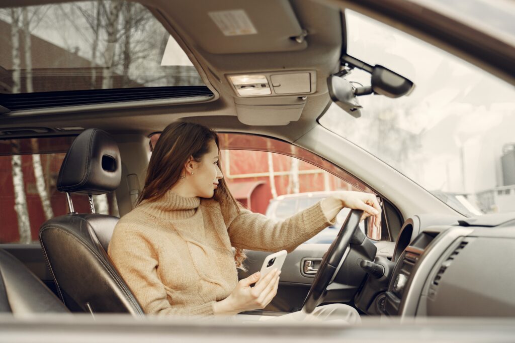 A woman in a beige sweater is driving a vehicle.