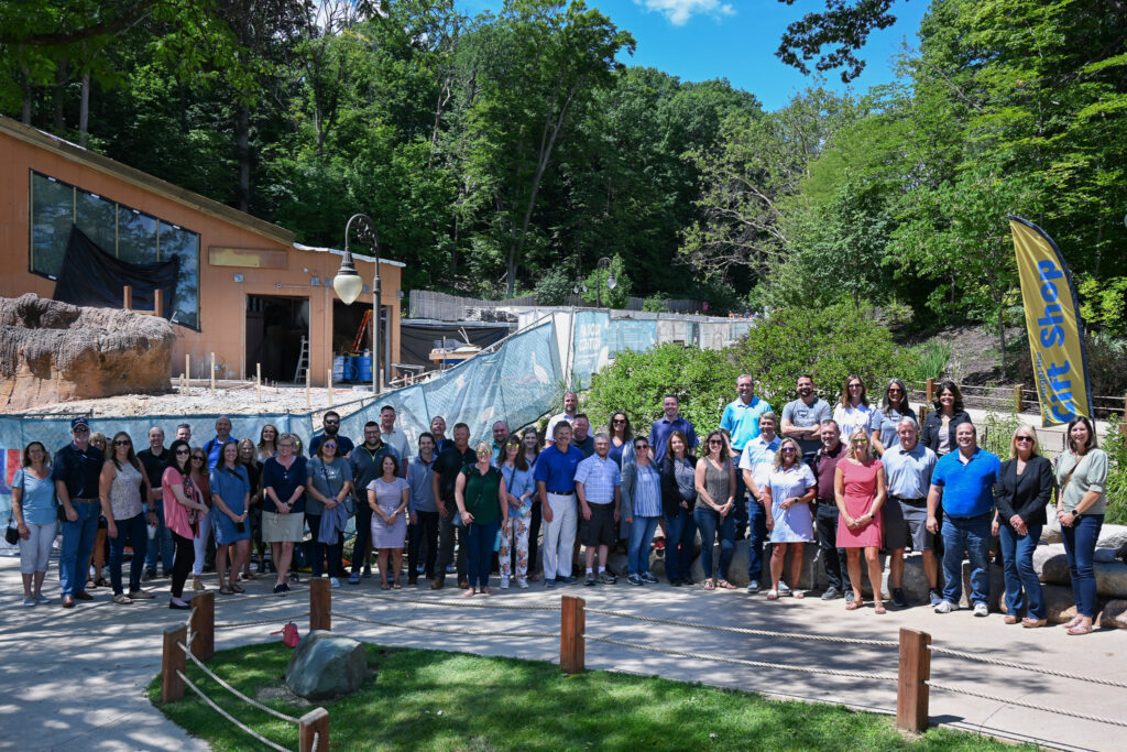 Consumers Credit Union staff pose for a group photo in front of the John Ball Zoo construction site for the future pygmy hippo habitat.