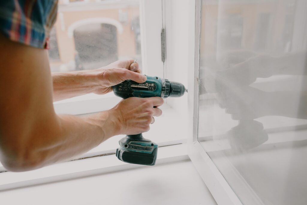 A person using a drill to fix a window pane.