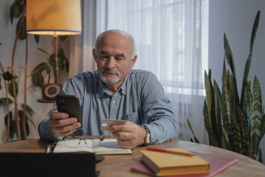 A middle-aged man typing his credit card information into his phone.