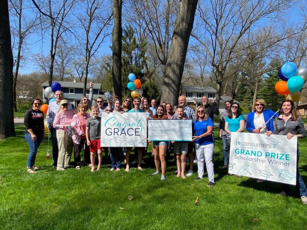 large group gathered with signs and balloons to announce the 2022 Consumers Scholarship Winner