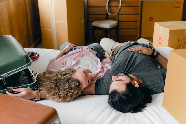 Multiethnic couple lying down on a bed at their home after unpacking