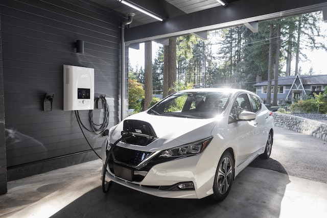 A white electric vehicle charging in an open garage.