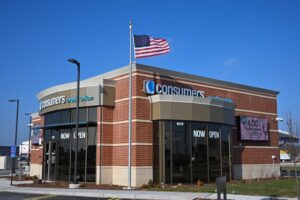 Consumers Credit Unions' new Delta Crossings office in Lansing, a brick building with tall windows and the American flag waving in a clear blue sky.