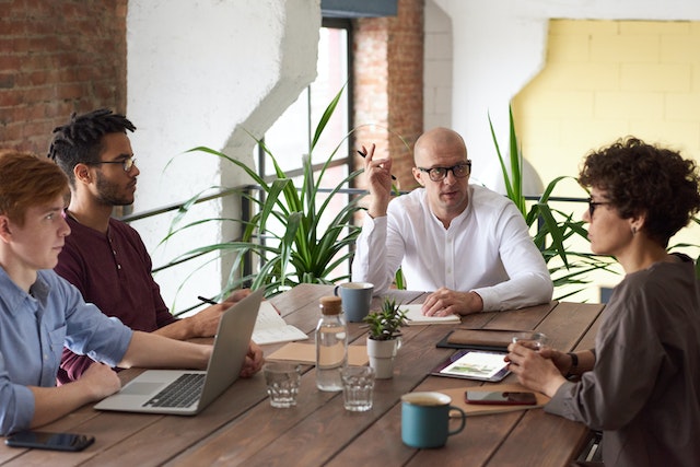 Four business professionals sit around a conference table as they collaborate during a meeting.
