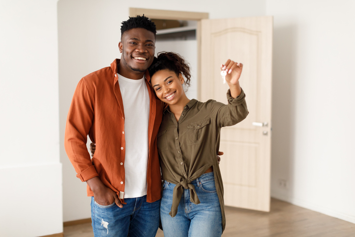A couple stands inside their empty, new home as they hold their new set of house keys.