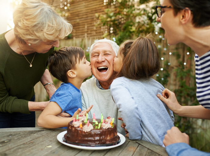 Elderly man celebrating his birthday with his family and young grandchildren.