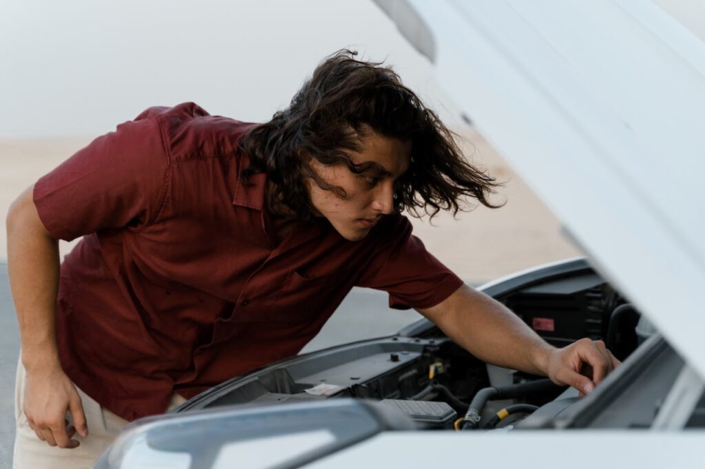 Person looking under the hood of a car.