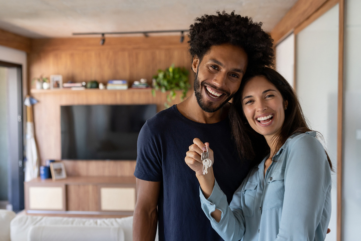 Happy young man and woman smiling while holding up keys.