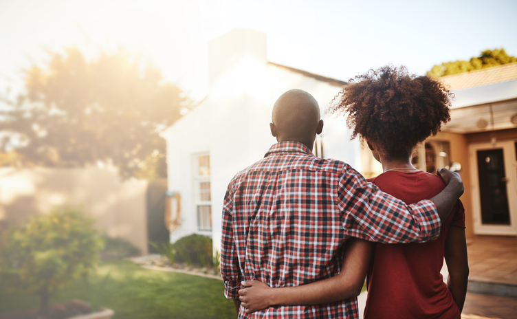 Man and woman with their backs turned looking at a house.