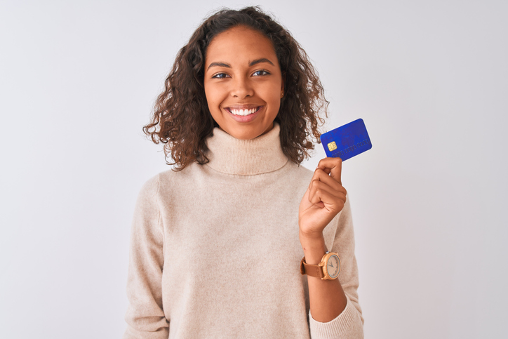 Young woman smiling while holding up a credit card.