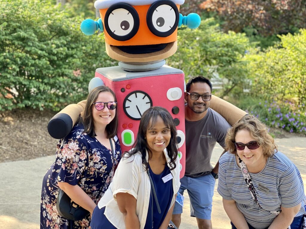 Consumers employees standing and smiling with Wimee the Robot.