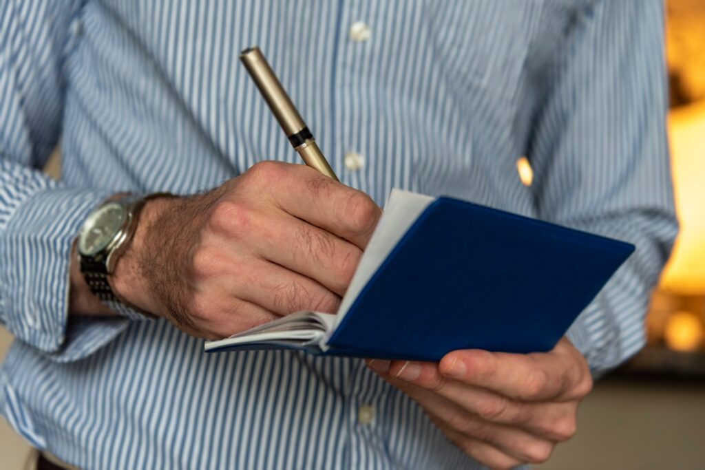 Man standing and filling out a check in his checkbook.