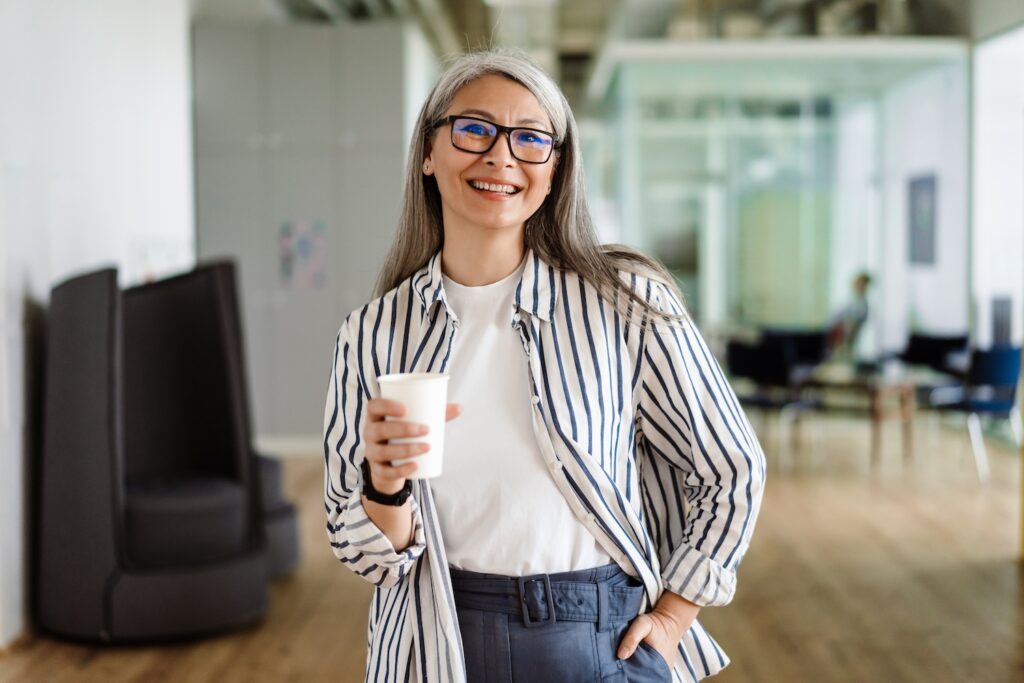 Mature woman smiling while holding a cup.
