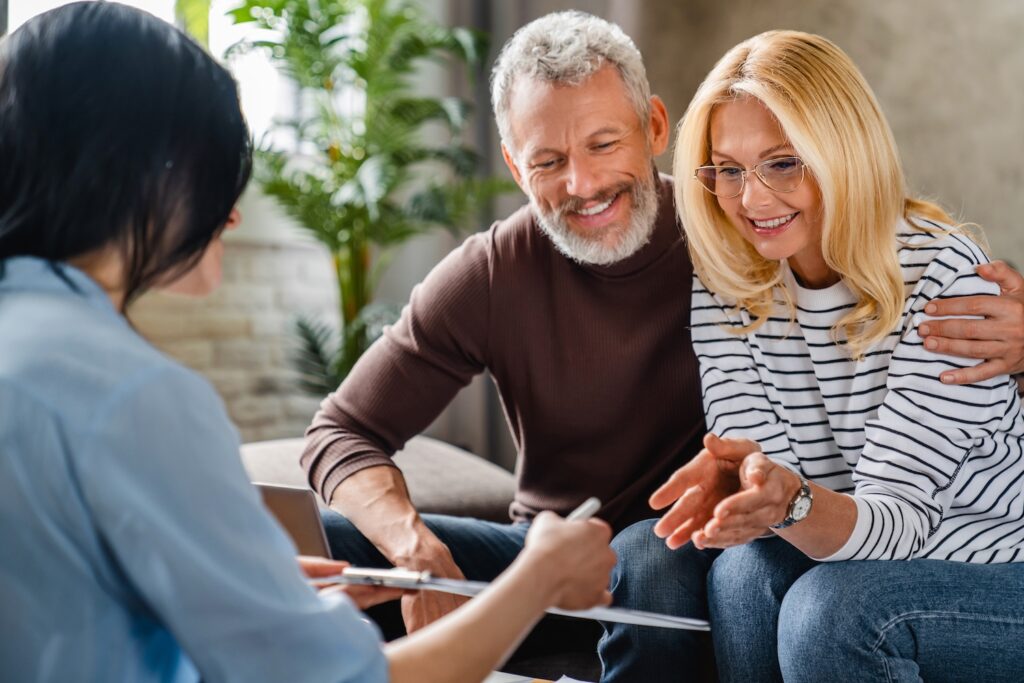 Mature couple smiling while talking with a financial representative.