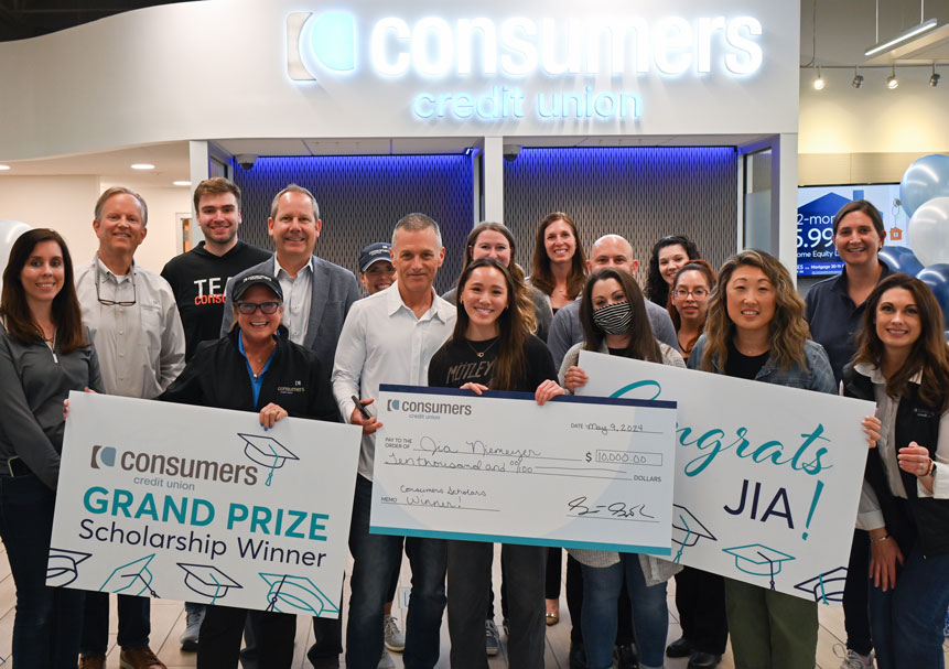 Scholarship winner celebrates with group and large check.