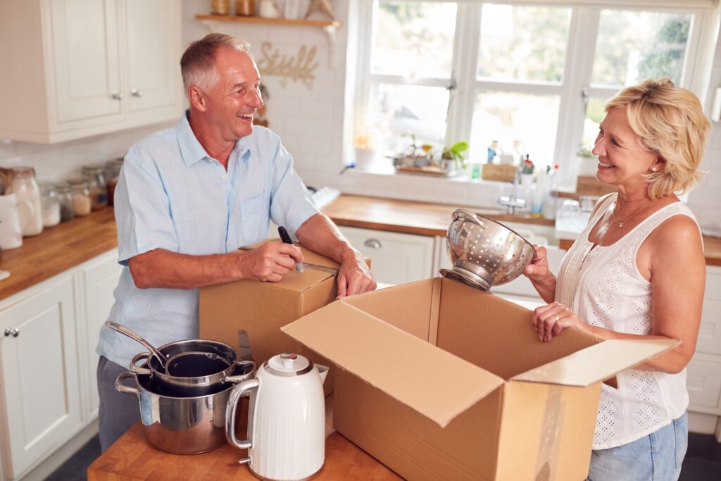 Mature couple smiling while packing items into boxes.